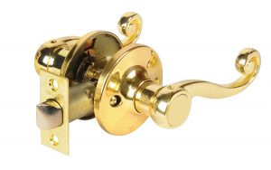 Polished brass door handle with lock and ornate design against a white background.