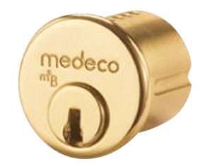 Brass Medeco security lock cylinder on a white background.