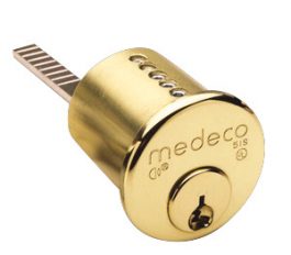 Gold Medeco brand lock cylinder on a white background.