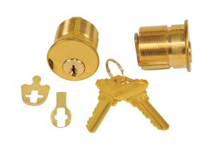 Gold cylinder lock with keys and disassembled parts on white background.