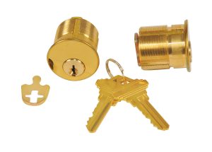 Gold-colored cylinder lock with keys and key core components on a white background.
