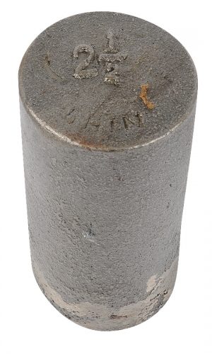 A cylindrical metal weight with markings on the top surface.