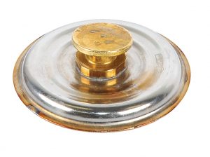 A clear glass and gold-colored metal lid from a perfume bottle.
