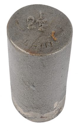 A cylindrical metal weight with stamped markings on the top surface.