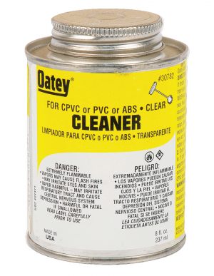 A can of Oatey clear cleaner for CPVC, PVC, or ABS pipes with safety warnings on the label.