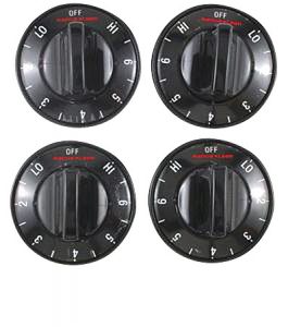 Four black stove control knobs with white markings on an isolated background.