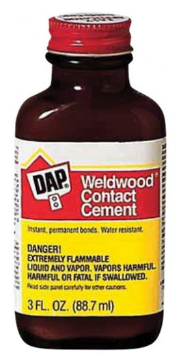 A bottle of Weldwood contact cement with safety warnings and a red label.