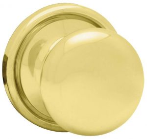 Polished brass round door knob on a plain background.
