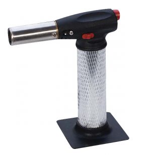 A handheld culinary torch with a black grip and a metallic nozzle, on a stand.