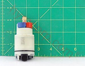 Electric fuel pump component on a green cutting mat with grid measurement background.