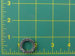 Metal washer on a green cutting mat with grid and ruler markings.