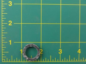 Metal washer on a green cutting mat with grid and ruler markings.