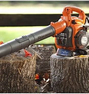 An orange leaf blower resting on a tree stump with scattered leaves around.