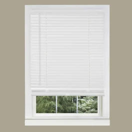 White window blinds partly open with a view of green trees outside.