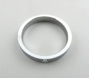 A simple silver metal ring with a flat edge and a small screw on a plain background.