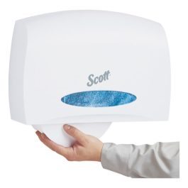 Hand reaching for paper from a Scott brand wall-mounted hand towel dispenser.