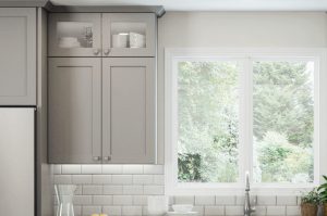 Modern kitchen interior with grey cabinets and a window view of greenery.