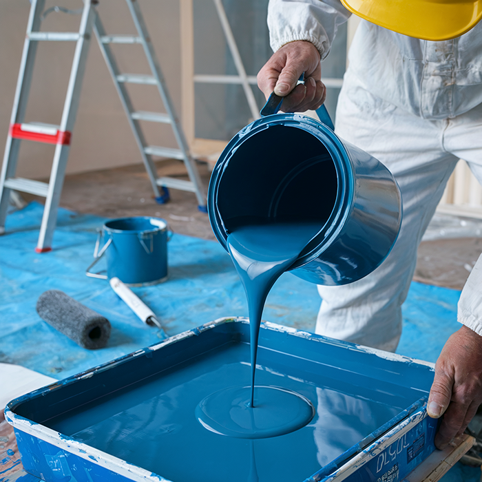 worker pouring oil based paint into paint tray